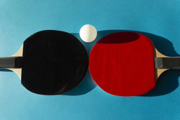 Table tennis bats and ball on blue copy space