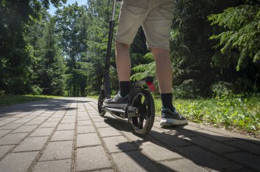 Genç parkta yolda siyah tekme scooter sürme