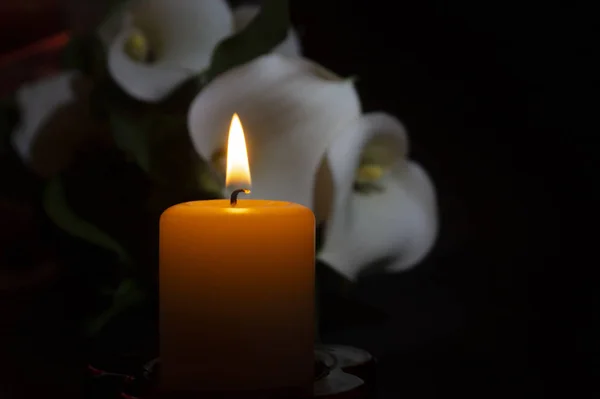 Nahaufnahme orangefarbener Kerzenflamme und Lilienblüten — Stockfoto