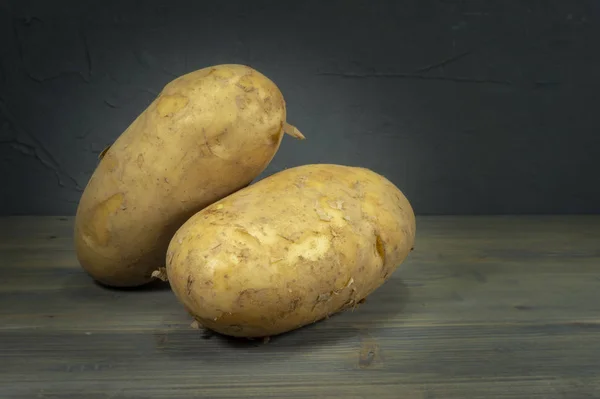 Batatas frescas colhidas em tábua de madeira rústica — Fotografia de Stock