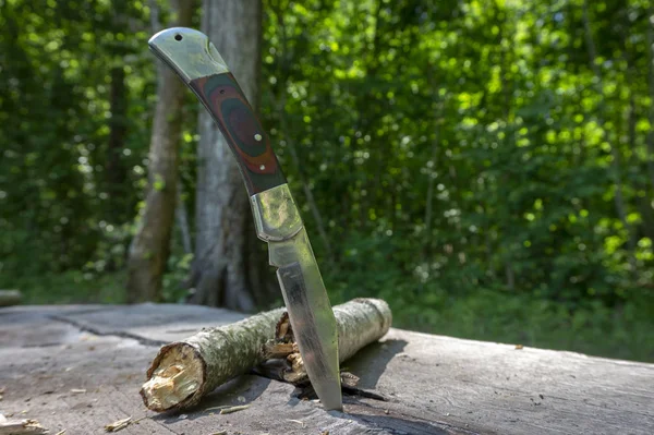 Składany nóż zatrzymany pionowo w starym stole piknikowym — Zdjęcie stockowe