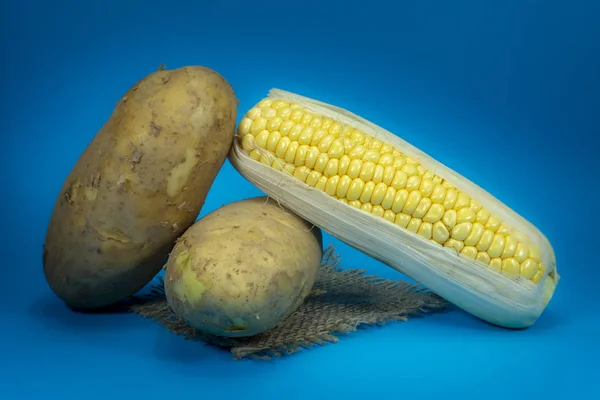 Sweetcorn cob and potatoes on a square of hessian — Stock Photo, Image