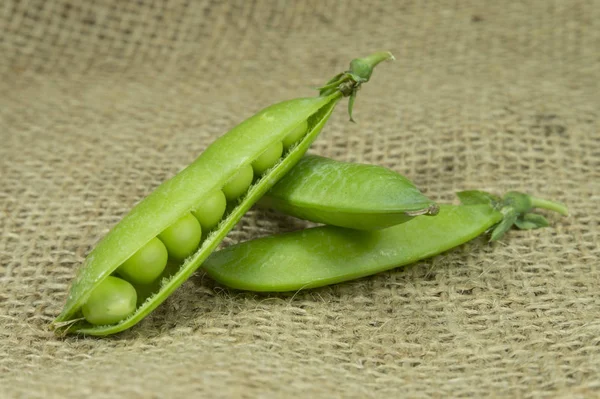 棕色黄麻背景上的新鲜绿色豌豆豆 — 图库照片