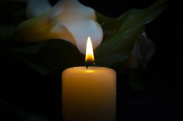 Primo piano di fiamma di candela arancione e fiori di giglio — Foto Stock