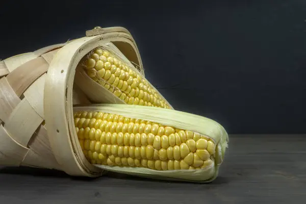 Sweetcorn cobs spilling out of tipped wicker basket — Stock Photo, Image