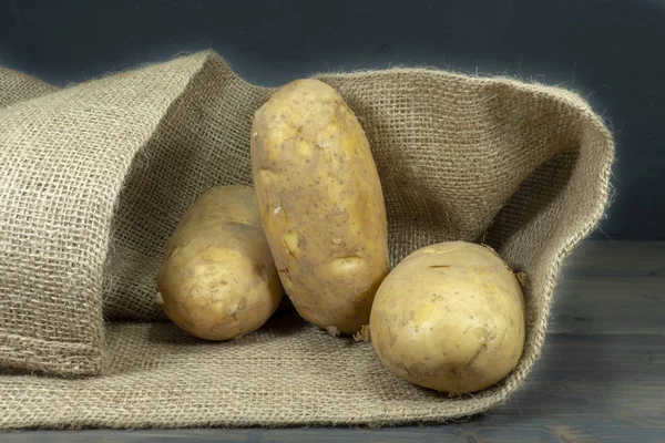 Batatas, derramando fora do saco hessiano — Fotografia de Stock