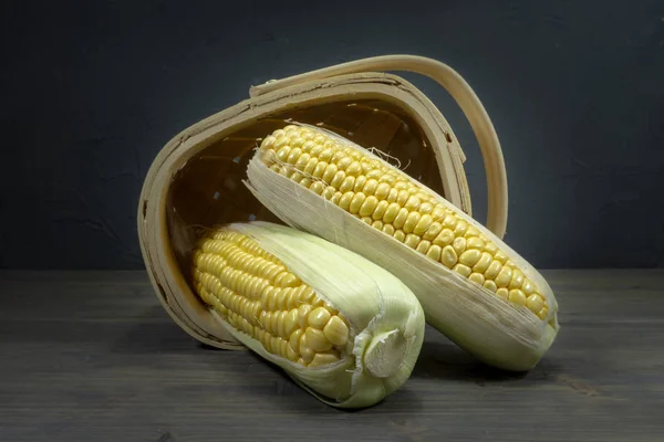 Sweetcorn cobs spilling out of tipped wicker basket