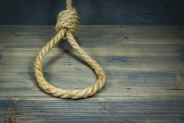 Hangman's knot on a rustic wooden table — Stock Photo, Image