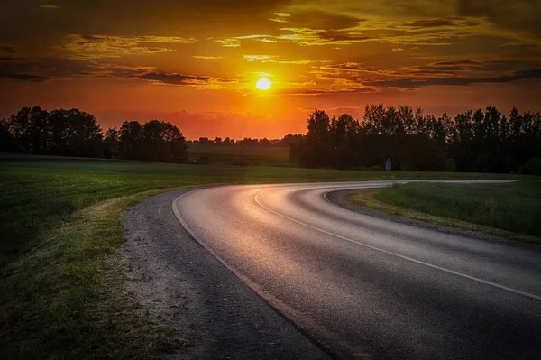 Vivid orange tropical sunset with curving road — Stock Photo, Image