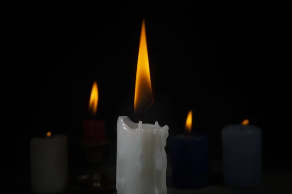 Hořící svíčky z různých barev v temnotě — Stock fotografie
