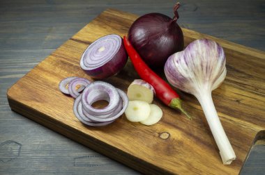 Kesme tahtasında soğan, sarımsak ve biber.