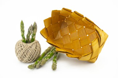 Taze yeşil kuşkonmaz demeti, sade örülmüş sepet ve beyaz arka planda izole edilmiş kenevir sicimi topağı, düşük açı görünümlü seçici odak