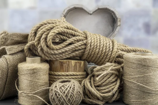 Assorted balls of jute twine and string with skeins of rope in a close up rustic still life