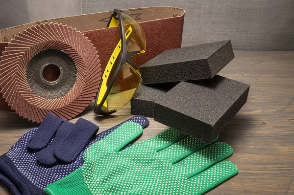 Different tools for sanding - sanding belt, clamps, abrasive sponge and flap disc for angle grinder, safety gloves and goggles, renovation, safety and health at work concept