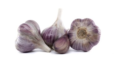 Birkaç sarımsak ampulü yakın çekim, bir karanfil ayrılmış, temiz beyaz bir arkaplan üzerine kurulmuş. Resim dokuyu ve ayrıntıyı vurgular.