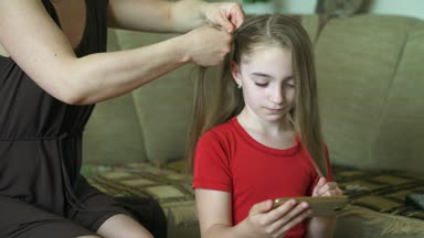 Kadının elleri küçük kızı için saç modeli yapmak. Bir kadın kızı için saç örgü.