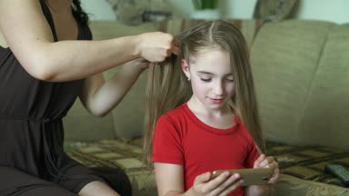 Kadının elleri küçük kızı için saç modeli yapmak. Bir kadın kızı için saç örgü.