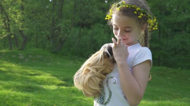 Enfant fille blonde tenant son cobaye animal de compagnie. Des images à la main à l'extérieur. L'été. — Video