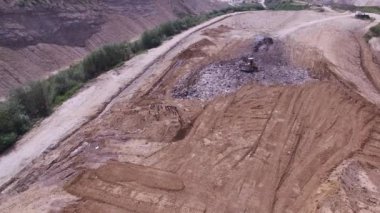 Kazıcı çöp hurdalıkta taşır. Hava atışı.