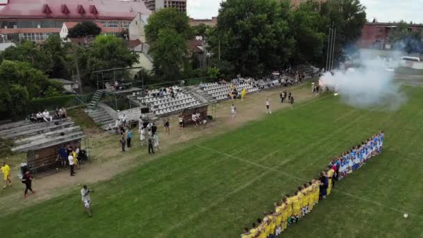 Lviv, Oekraïne - 28 juni 2019 Twee amateurvoetbalteams die volksliederen luisteren voor voetbalwedstrijd op amateurtoernooi. Luchtfoto. — Stockvideo