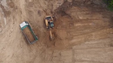 Hava üst görünümü: Sarı kazıcı toprağı bahşiş verenin içine döküyor.