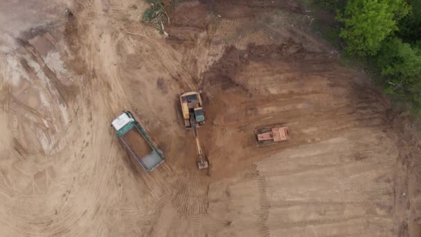 空中俯瞰：黄色挖掘机将土壤倒入倾卸机中 . — 图库视频影像