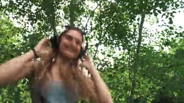 Menina bonita, com fones de ouvido na cabeça dançando ao som da música, vídeo em câmera lenta — Vídeo de Stock