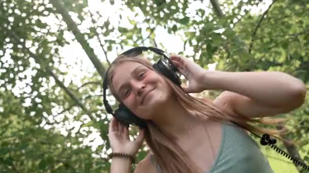 Hermosa jovencita con auriculares escuchando música y bailando, de cerca, en cámara lenta — Vídeos de Stock