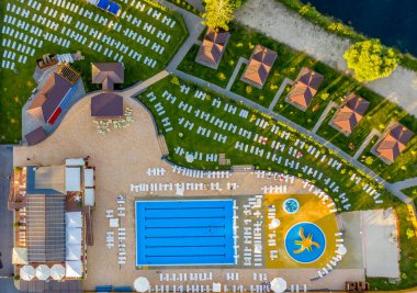 Havuzu ve güneşli yatakları olan terk edilmiş bir dinlenme alanının havadan çekilmiş fotoğrafı.