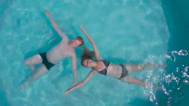 空中照片，一个男的和一个女的躺在水面上的一个游泳池里 — 图库视频影像