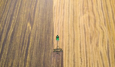 Hava fotoğrafı, tahıl hasadından sonra tarlayı süren bir traktör..