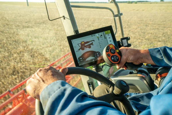 Gün batımında bir arpa tarlasında tahıl hasat etmek, modern bir hasat makinesinin dümeninde biçerdöver, tahıl, yakın çekim direksiyonu ve joystick 'i birleştirmek.