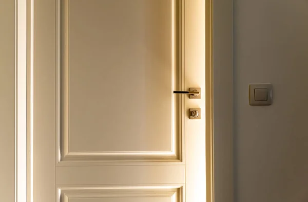 Parlak ışık demetleri kapıdaki bir çatlaktan geliyor.