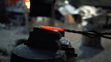 Demirci, demirci çekiçli, sıcak, kırmızı bir demir çubuk döver.