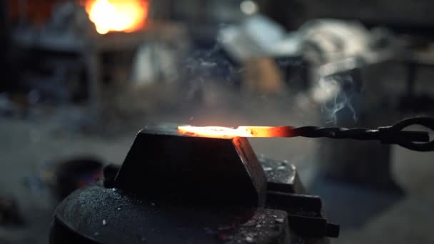 A blacksmith forges a red hot metal billet with a blacksmiths hammer — Stock Video
