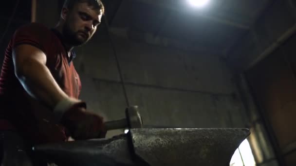Un fabbro usa un martello a mano su un'incudine per forgiare un prodotto di metallo caldo rosso — Video Stock