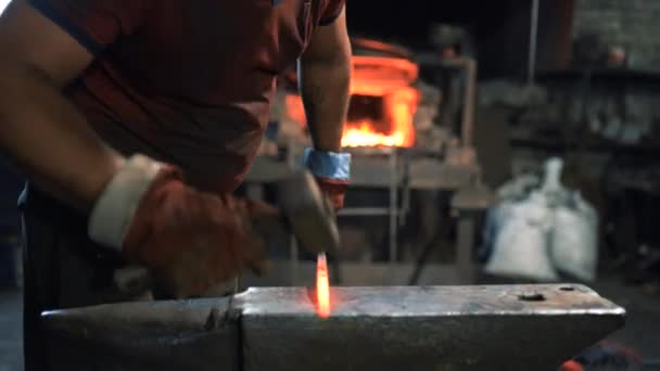Um ferreiro usa um martelo de mão em uma bigorna para forjar um produto de metal quente vermelho — Vídeo de Stock