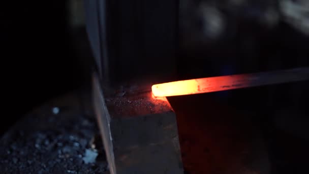 Un herrero forja una palanquilla de metal caliente rojo con un martillo herrero — Vídeos de Stock