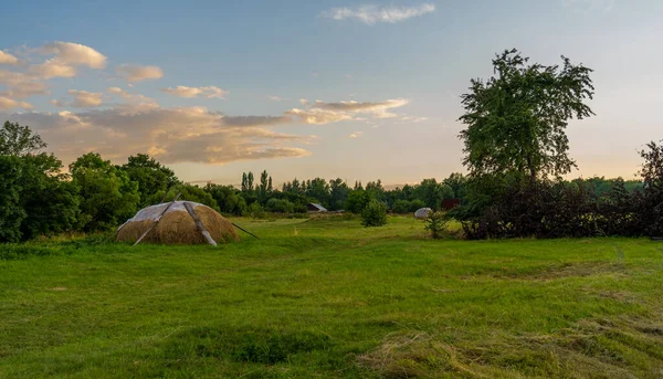 Evening village landscape with a haystack on the background of the sunset — Stock Photo, Image