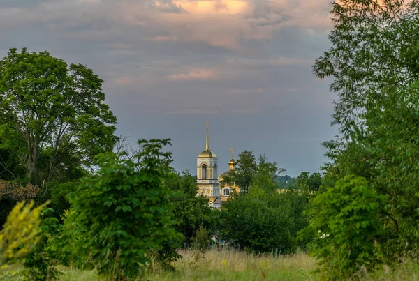 Yaprakların arasında bir Ortodoks Kilisesi olan akşam köyü manzarası