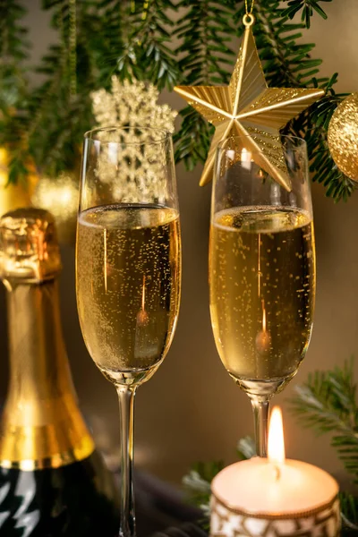 Şampanya kadehli Noel süsü, altın oyuncaklarla süslenmiş Noel ağacı ve yanan bir Noel mumu, tebrik kartı.