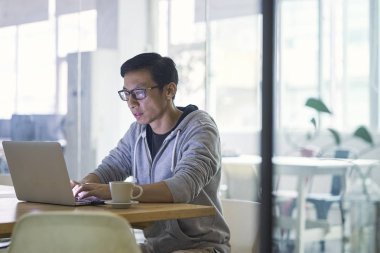 Ofiste bilgisayar, arkadan aydınlatmalı doğal aydınlatma tarafından çalışma Asya işadamı portresi