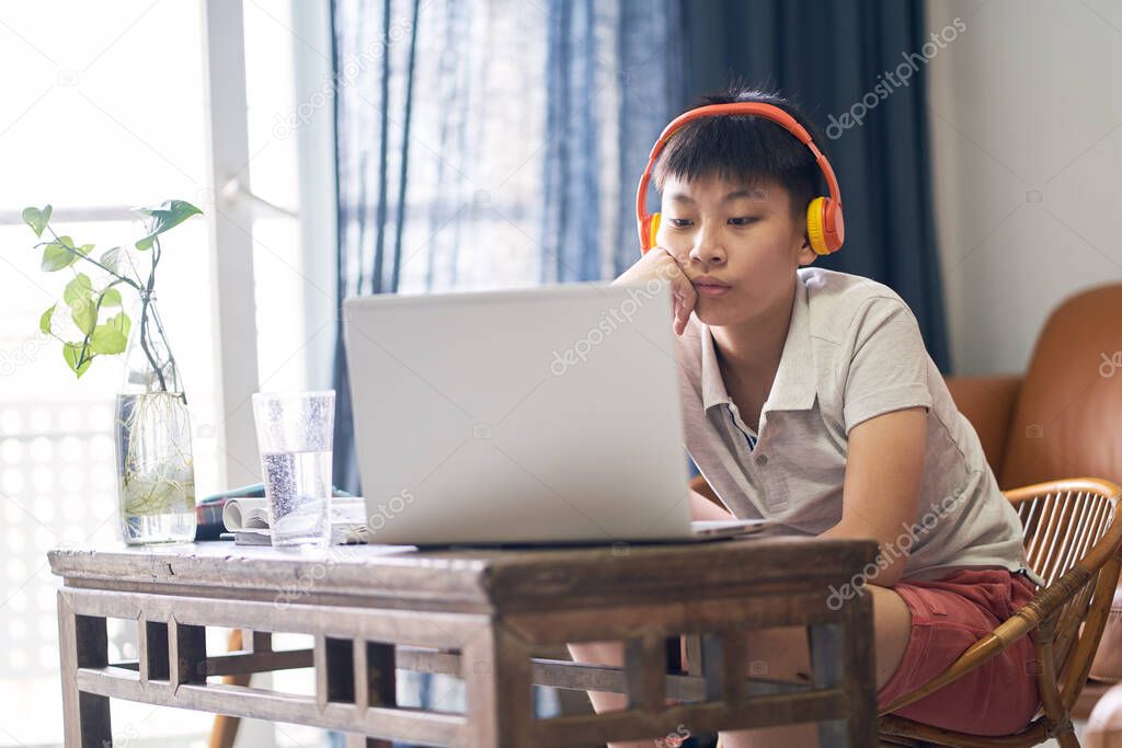 Asian kid taking online class at home smiling & wearing headset