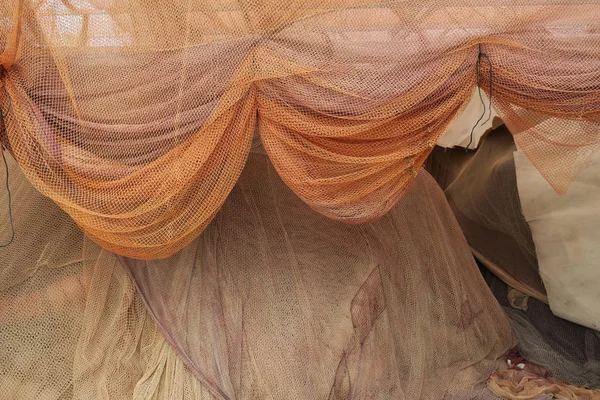 orange colored draped fishing nets hanging out like a veil