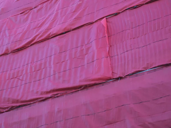 Edificio rodeado de andamios cubiertos de tela roja — Foto de Stock