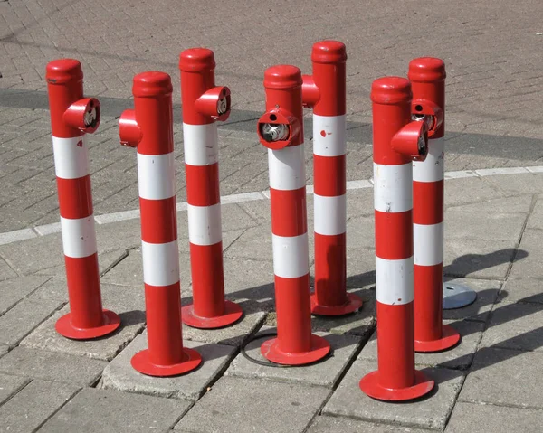Raccolta di post rossi e bianchi sul marciapiede lungo la strada — Foto Stock