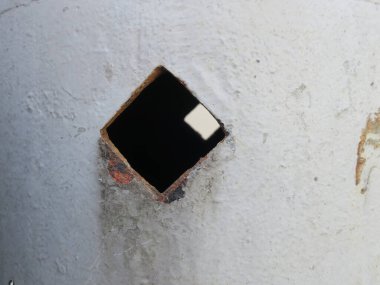 Gri bir demirin üzerinde iki kare delik.