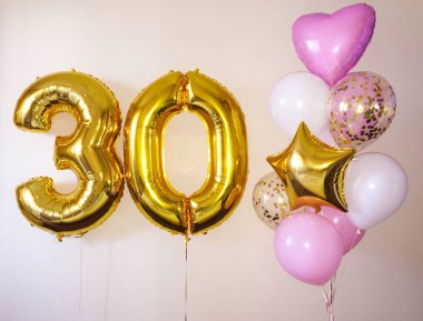Beyaz, pembe, konfeti, şeffaf yanı sıra altın yıldız ve büyük bir rakam otuz altın renk kompozisyonu helyum balonlar. 30 yıl boyunca bir kız için hediye