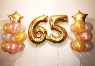 Helyum balon altın, pembe ve konfeti, altın yıldızlar ve büyük rakamlar altmış beş altın renk şeffaf bir kompozisyon. 65 yaşında bir kadın için Hediyelik