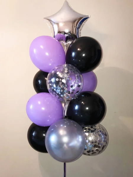 Composition of helium balloons lilac, silver, black, as well as transparent with silver confetti. Decorating the room for a party